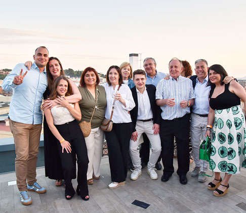 Once personas posando juntas en una terraza al aire libre, sonriendo y abrazándose